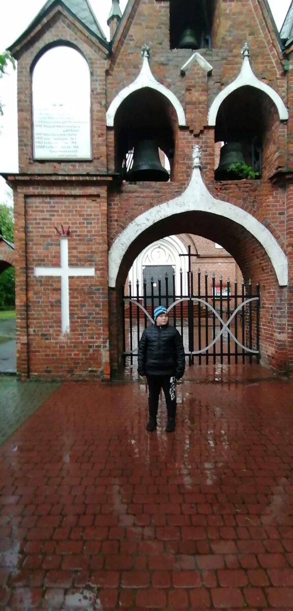 Chłopiec na tle dzwonnicy.
