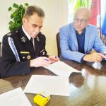 Dwóch mężczyzn, jeden z nich podpisuje dokument