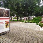 Plansza wystawowa z napisem "Biel i czerwień", w tle park