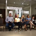 Pan Wójt czyta, reszta uczestników siedzi z zaciekawieniem słuchając. W tle eksponaty Muzeum Konstantego Laszczki