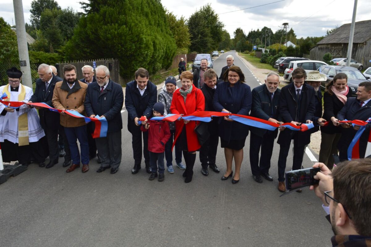 Kilkanaście osób stojących obok siebie, przed nimi wstęga w kolorach biało - czerwonych