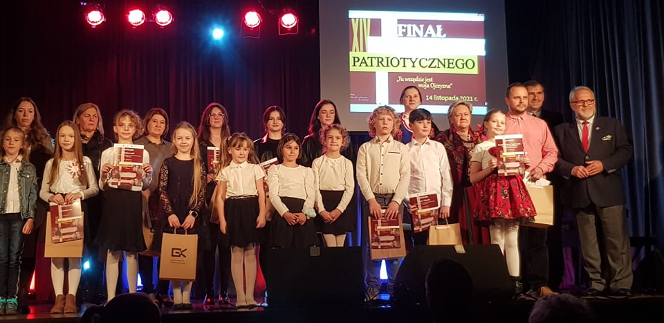 Kilka osób w młodym wieku na scenie w towarzystwie mężczyzny w garniturze