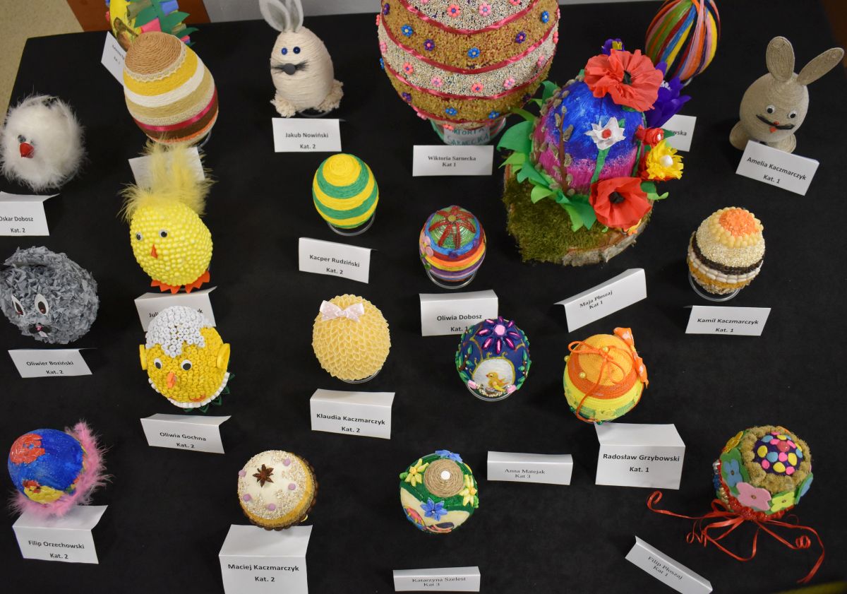 Na czarnym tle stoją kolorowe pisanki.