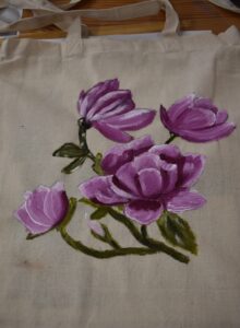 Płócienna torba na której namalowane są różowe magnolie z zielonymi listkami