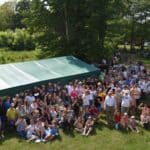 Wszyscy uczestnicy rajdu pozują do zdjęcia za nimi zielony namiot i wysokie drzewa