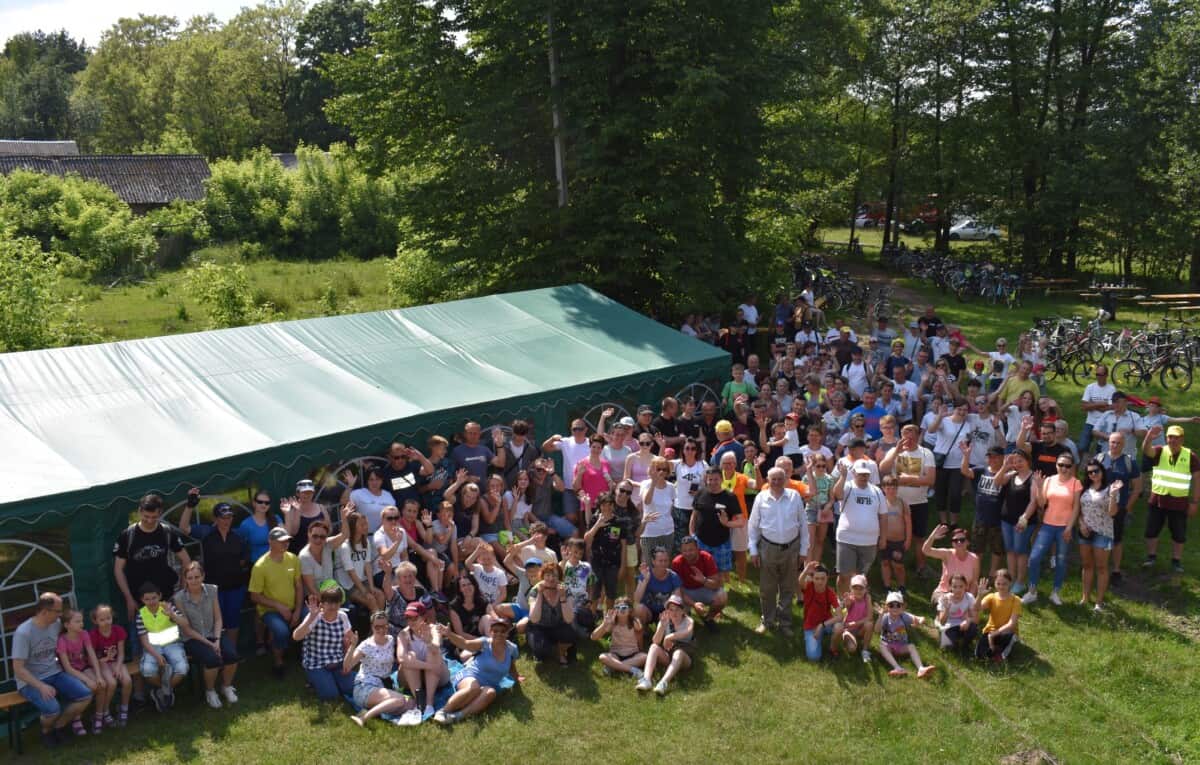Wszyscy uczestnicy rajdu pozują do zdjęcia za nimi zielony namiot i wysokie drzewa