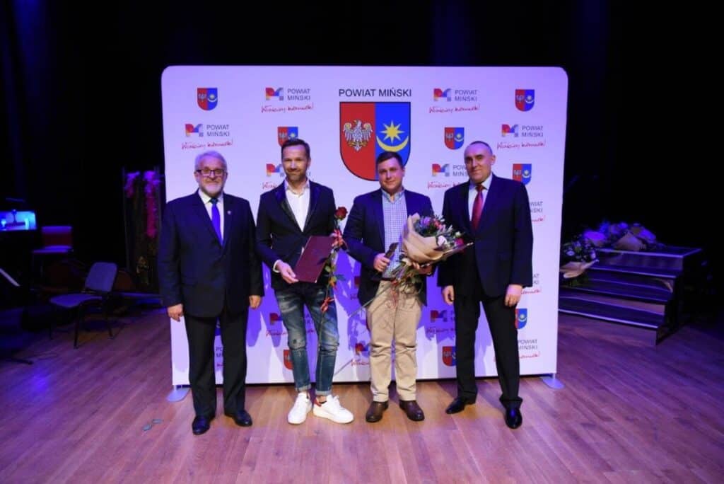 Czterech mężczyzn z nagrodami w odświętnych strojach