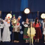 Kilkanaście osób na scenie w przebraniach aniołów.