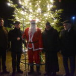 DSC_0165 Pięciu mężczyzn stojących obok siebie. W tle drzewko świąteczne.