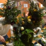 396 Biały pleciony wianek z dużą ilością gałązek tui, złotymi bombkami.