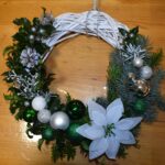432 Pleciony wianek ozdobiony białymi bombkami i zielonymi oraz gałązkami jodły, świerku, ostrokrzewu, szyszek i białą gwiazdą betlejemską.