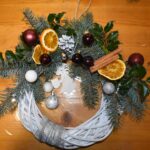 438 Pleciony wianek ozdobiony srebrnymi i bordowymi bombkami, szyszkami, pomarańczami, cynamonem.