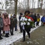 Trzech mężczyzn składających kwiaty przy pomniku