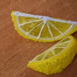 Uśmiechnięte dzieci pozują do zdjęcia z zrobionymi przez siebie skrzatami i magnesami. W tle biblioteczne regały z książkami.