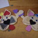 195 Przy długim stole siedzą dzieci i jedzą pizze którą same przygotowały, popijają soczkiem. Na środku stoją tace z kawałkami pizzy. W tle regały z książkami