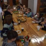 Dzieci siedzą przy stole na którym leżą kartki i duże długopisy do rysunku 3D