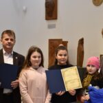 $ osoby dorosłe oraz kilkunastoletnia dziewczynka. Kobieta trzyma dyplom.