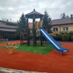 Niebieska zjeżdżalnia, w tle żółty budynek