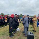 mężczyzna wręczający nagrodę strażakowi