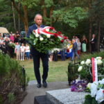 kwiaty biało czerwone grób zielona trwawa ludzie