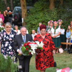 kwiaty biało czerwone grób zielona trwawa ludzie