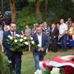 kwiaty biało czerwone grób zielona trwawa ludzie