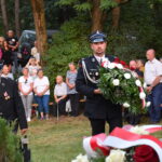 kwiaty biało czerwone grób zielona trwawa ludzie