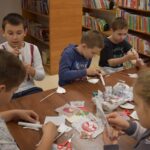 Na zielonym dywanie stoi kula a dzieci siedzące w kole dotykają ją rękoma