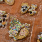 Dzieci w Bibliotece na drewnianym stole zabierają się do pieczenia pierników. W tle regały z książkami