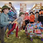 263 Bawiące się dzieci w bibliotece na zielonym dywanie stoi papierowy kolorowy dzik.