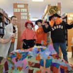 264 Poprzebierane dzieci za postacie z bajek, na pierwszym planie kolorowy dzik z bibuły. W tle regały z książkami