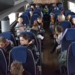 116 W autokarze siedzą dzieci na niebieskich siedzeniach