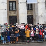 173 Grupka zadowolonych dzieci macha rękoma. W tle kolumny budynku