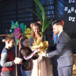 Na zdjęciu mężczyźni w garniturze, który jest prezentem grupy dzieci. Wygląda na to, że dzieje się coś wyjątkowego lub świętowanie.