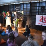 Na wolności jest grupa dzieci siedząca na scenie. W tle można wyodrębnić część sceny, która stanowi ich tło do występu.