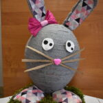 1-Miejsce-w-2-kategorii Na obrazku dekoracyjnym wielkiego królika, wykonanego z szarego i różowego materiału, który jest wystawiony na pościel z sztucznych trawy. Królik ma sympatyczną minę i brzmi na delikatnym w dotyku.