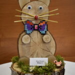 2-Miejsce-w-2-kategorii Na urządzeniu jest zainstalowane oprogramowanie komputerowe z oprogramowaniem, które obejmuje pracę z koralikami. Figurka jest prezentowana na podstawie kawałka drewna.