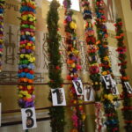 Na zdjęciu są kolorowe, ozdobnie przyozdobione palmy wielkanocne pionowo wystawione w kościele. Oznaczone z nich jest oznaczeniem, co wskazuje na udział w zawodach.