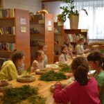 Na dzieciach udział w warsztatach plastikowych w bibliotece, pod kierunkiem instruktora. Młodzi twórcy są skupieni na swoich projektach, a nauczyciel znajduje się w czymś, co jest dostarczane.