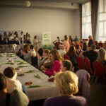 Na zdjęciu jest grupa ludzi siedzących przy stole. Daje się, że można je przygotować lub spożywać.