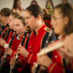 Na zdjęciu jest grupa ubrana w odpowiednie, czerwone mundurki, które grają na flecie. Powstał z nich, który składa się na twoją partię, tworzącą harmonijną melodię.