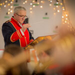 Obrazek przedstawia mężczyznę w morskim statku dyrygującym orkiestrą. początek od tyłu, z podniesionymi prowadzącymi, prowadzącymi muzykami grającymi na różnych instrumentach.