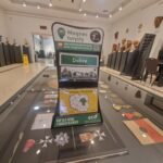 437741731_456034906772036_5242493750071978211_n Na widocznym jest magnes turystyczny wystawiony na ladę w sklepie z pamiątkami w muzeum. W tle są różne broszury informacyjne i inne przedmioty.