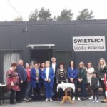 Zdj.-6 Na widocznej grupie osób, które są widoczne przed wejściem z napisem „świetlica wólka kokosia”. Budynek wydaje się być miejscem spotkań dla społeczności, a osoba może być zarejestrowana jako jego użytkownik lub pracownikmi.