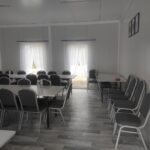 Zdjecie-3 Na obrazku widocznym pustą klasę z rzędami stolików i krzeseł, białe zasłony na oknach oraz szare podłogi. Po prawej stronie można umieścić dwie ramki zamocowane na ścianie.