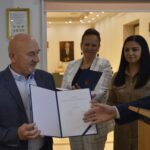 Na dowód formalną ceremonię wręczenia certyfikatu mężczyznom, podczas których dwie kobiety są monitorowane. Pokój, w którym znajduje się miejsce, w którym znajdują się udekorowane szklane gablotami oraz składniki dzieła sztuki.