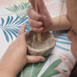 Na zdjęciach widać ręce, które tworzą gliniany garnek za pomocą drewnianego narzędzia. Wszystko to dzieje się na obrusie z ostatecznym rozwiązaniem.