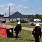 DSC_0223 Na obrazku dzieci ubranych w strażackie mundury uczestniczące w terenie torze oddzielne. Jedno dziecko czołgające się przez czerwony tunel, podczas gdy dwaj inni biegają w pobliżu.