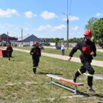 DSC_0303 Na trzech elementach wyposażenia użytkowego i hełmach wziąć udział w torze dostępnym na zewnątrz. Jeden z nich przez równoważnię, podczas gdy podążają za nim; w tle widoczny jest wóz strażacki i widzowie.
