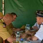 DSC_0329 Dane dotyczące mężczyzn w mundurach wojskowych siedzących przy stole, na których znajdują się notatniki i butelki z wodą. W tle występuje zielone tło, a grupa jest zaangażowana w zasięgu.